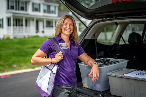 A cheerful individual stands beside their car, ready for the day ahead, with organized bins in the cargo area.