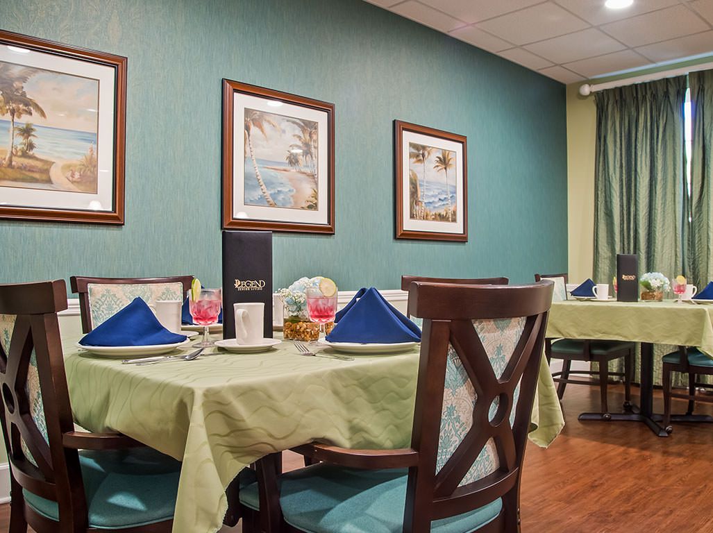 A cozy restaurant dining room with neatly set tables featuring blue napkins and framed artwork on the walls.