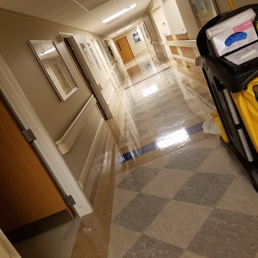 A clean corridor in a hospital, featuring mop buckets and polished floors.