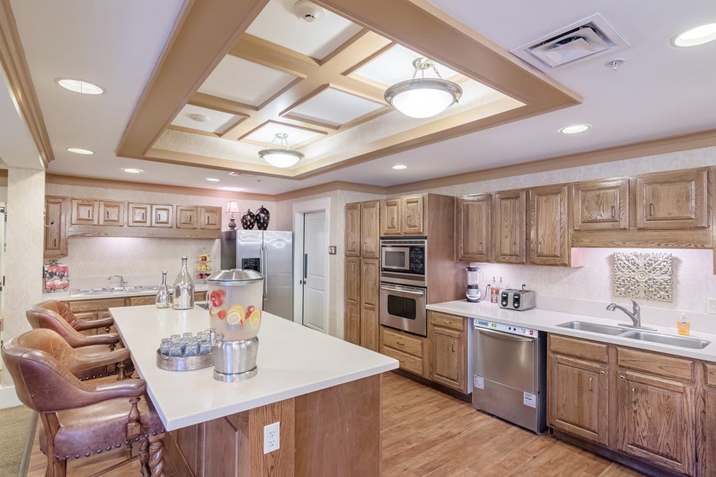A modern kitchen with wooden cabinets and a central island, featuring contemporary lighting and stainless steel appliances.