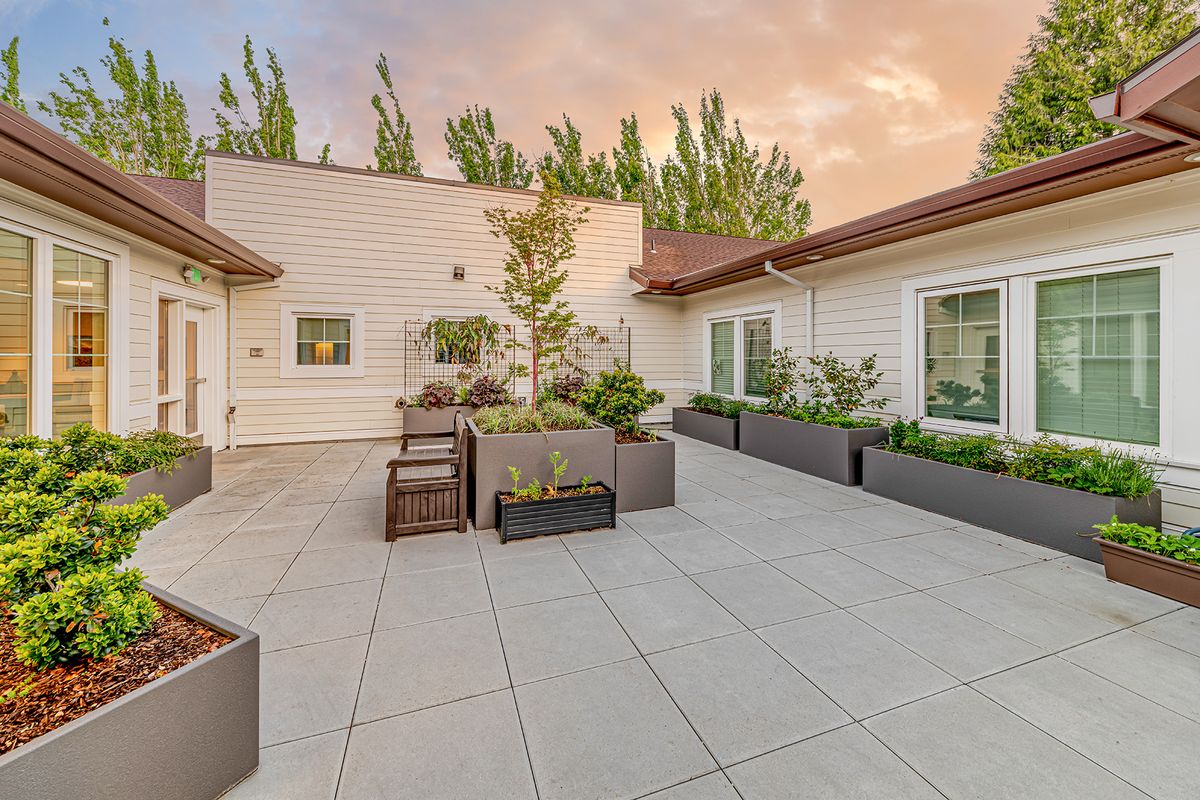 A modern outdoor patio area with planters under a colorful sunset sky.