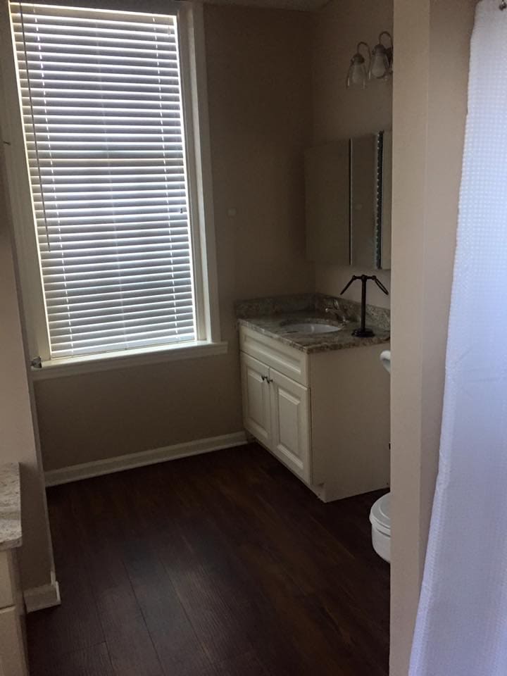 A small bathroom with a window, sink, and toilet.