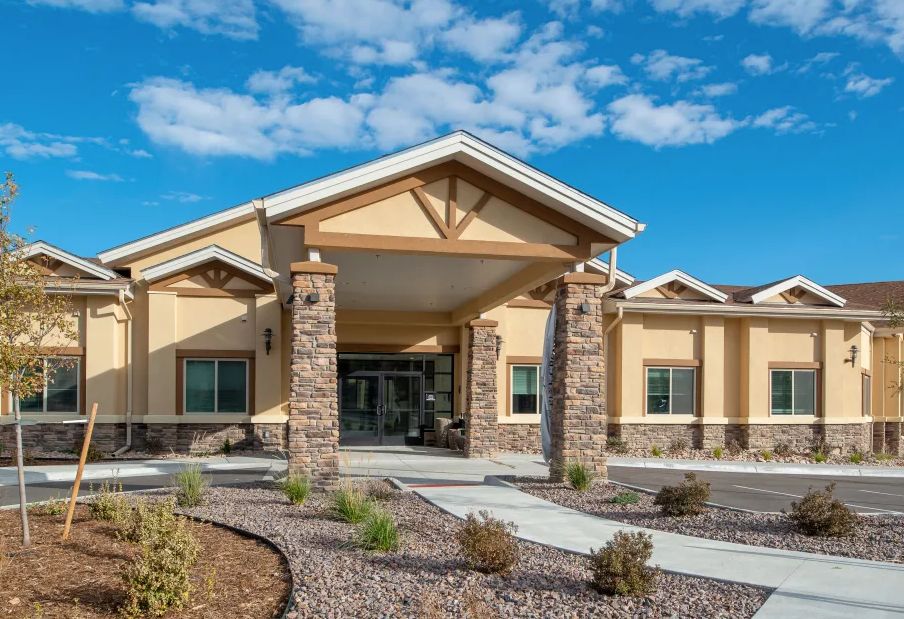 A modern building entrance with stone pillars and a landscaped front.