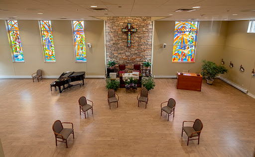 A serene church interior featuring stained glass windows and arranged seating for gatherings.
