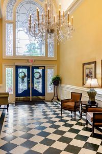 Elegant lobby with a checkered floor, chandelier, and inviting seating.