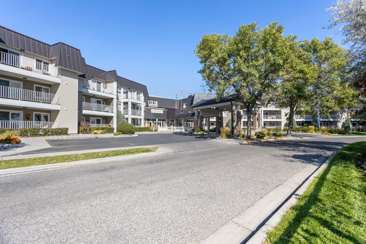 A suburban residential apartment complex with a tree-lined street and modern architecture.