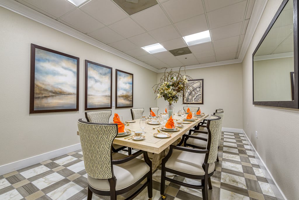 Elegant dining room with a beautifully set table, featuring decorative artwork and comfortable seating.