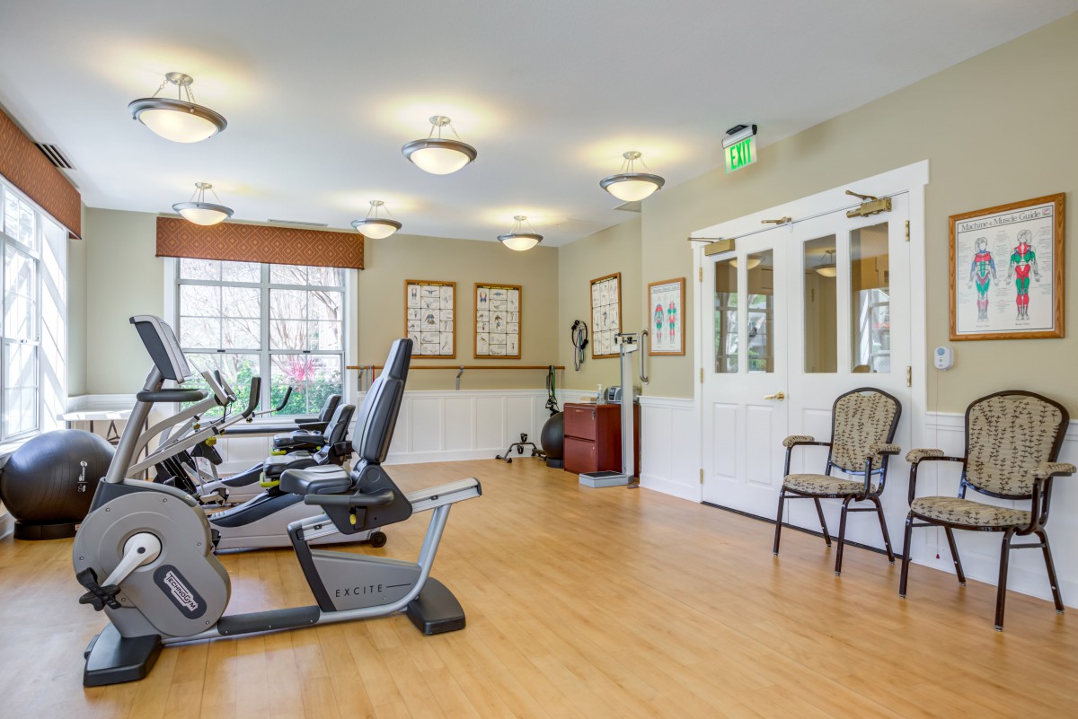 A well-lit exercise room featuring stationary bikes and wooden flooring.