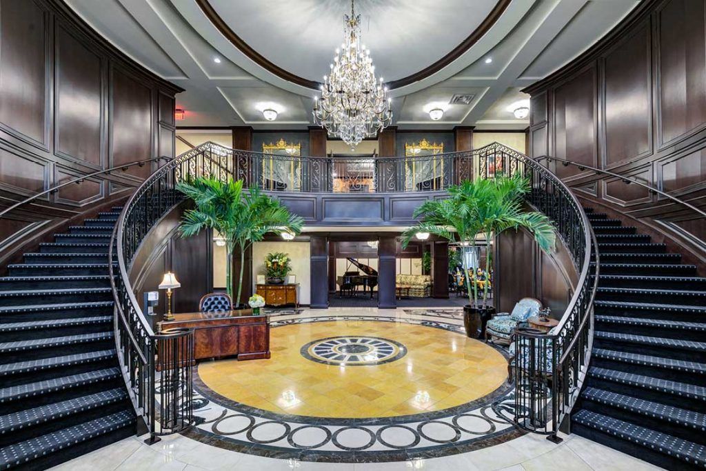 A luxurious hotel lobby featuring a grand staircase and elegant chandelier.
