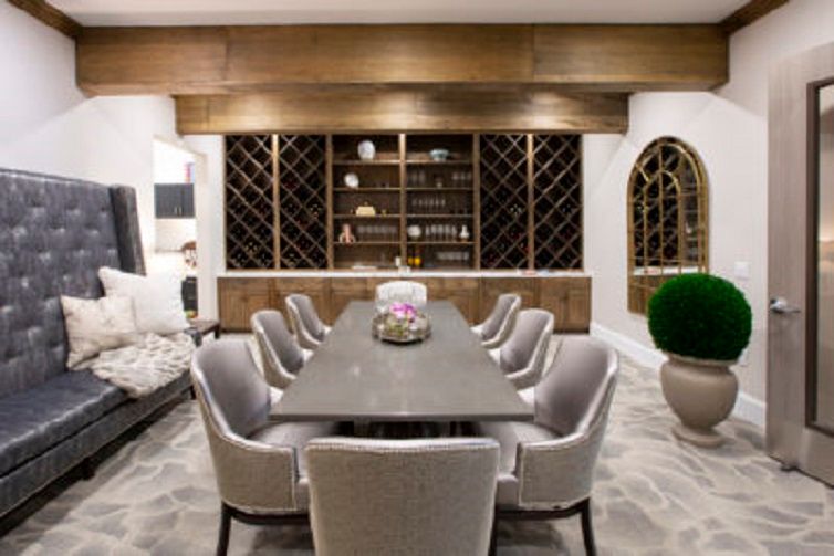 A luxurious and modern dining room featuring a long table, plush chairs, and an elegant wine rack on the wall.