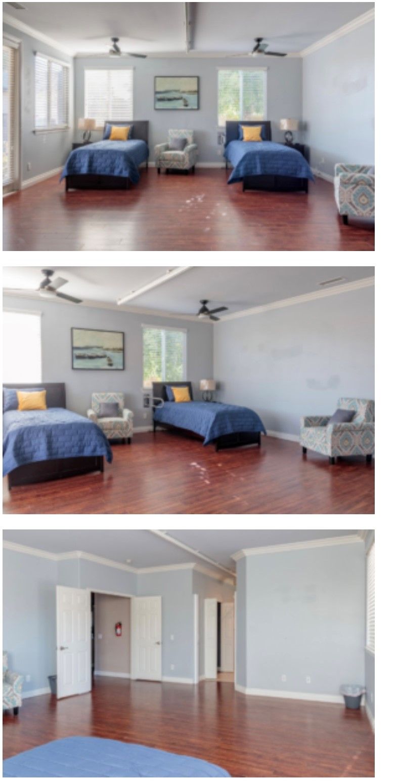 A spacious bedroom featuring two beds, armchairs, and ceiling fans on a hardwood floor.
