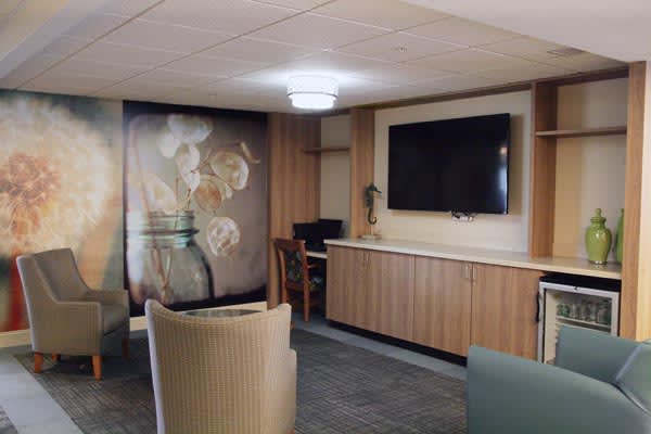 A modern lounge area featuring a large television, comfortable seating, and artistic wall decor.