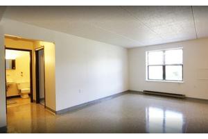 An empty room with a window and plain walls.