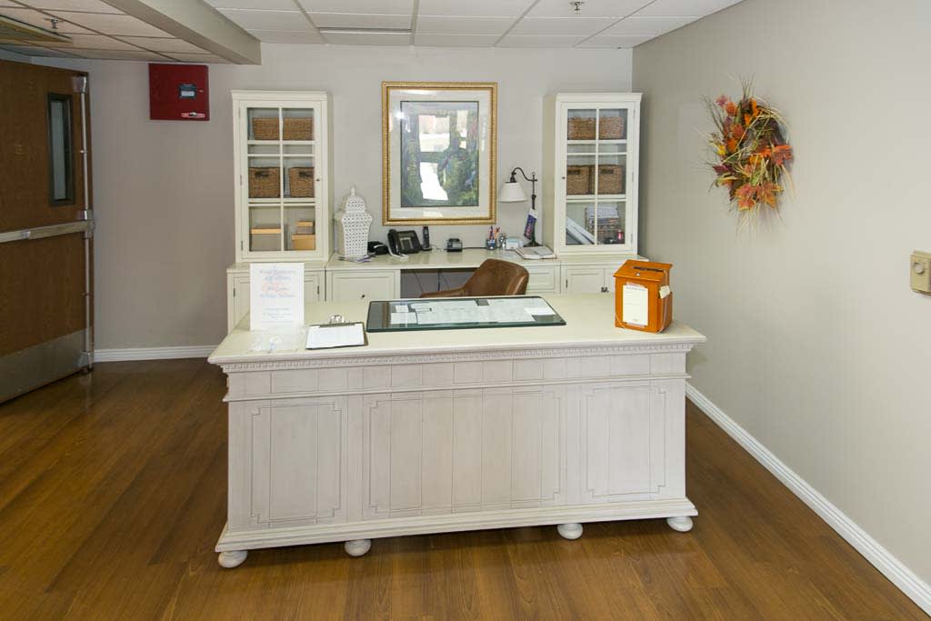 A neatly organized reception desk in an office setting with white furniture and decorative elements.