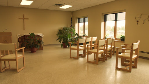 A serene waiting area with wooden chairs and a potted plant, bathed in natural light from the windows.