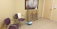 A cozy waiting area with chairs and a decorative cabinet.