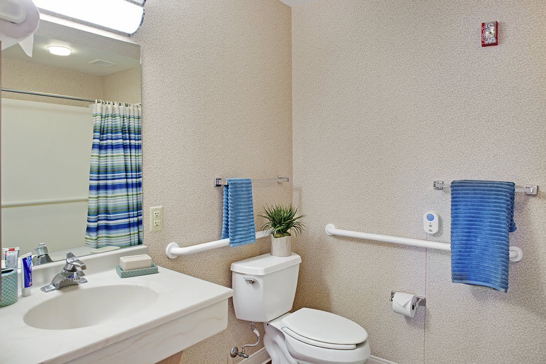 A clean and simple bathroom with essential amenities including a sink, toilet, and grab bars.