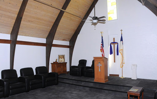 A view of a church sanctuary featuring a wooden pulpit, seating area, and religious symbols.