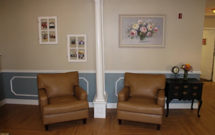 A cozy living room setting with two brown armchairs, decorative wall art, and a side table.