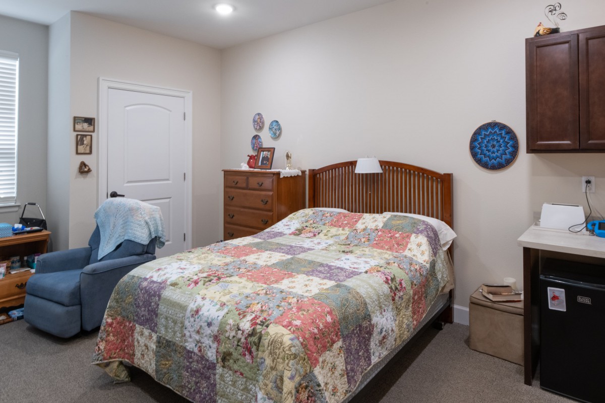 A cozy bedroom featuring a quilt-covered bed and wooden furniture.