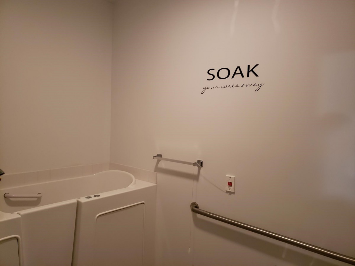 An accessible bathroom featuring a walk-in bathtub with handrails.