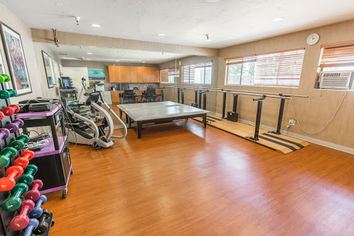 A spacious home gym equipped with various exercise machines and a large table for multi-purpose use.