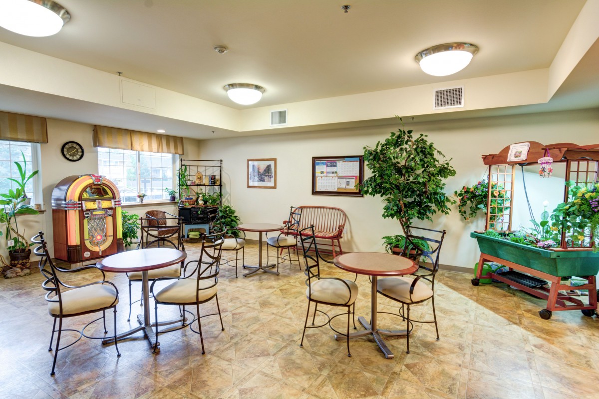A comfortable indoor seating area with tables and chairs, decorated with plants and artwork.