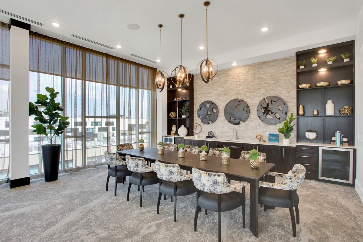 A modern dining room with a large table, decorative wall art, and floor-to-ceiling windows.