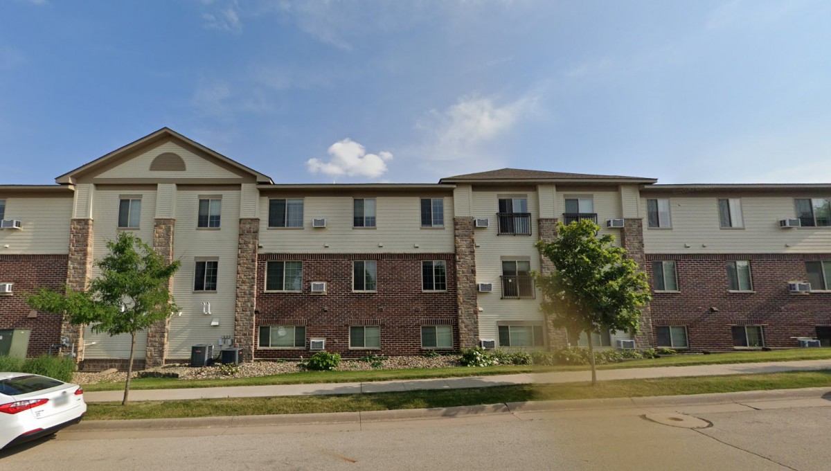 A three-story residential apartment building under a clear blue sky.