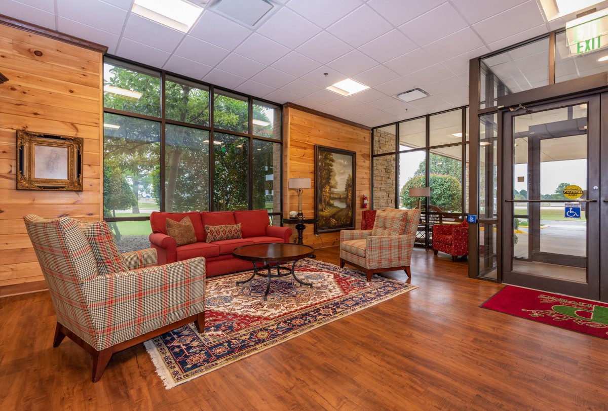 A cozy lobby with red sofas, armchairs, and large glass windows.
