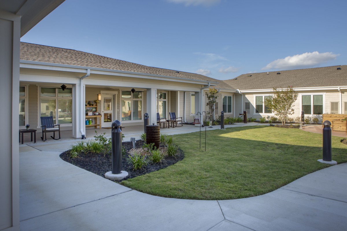 A well-maintained courtyard with a lawn and patio next to a modern building.
