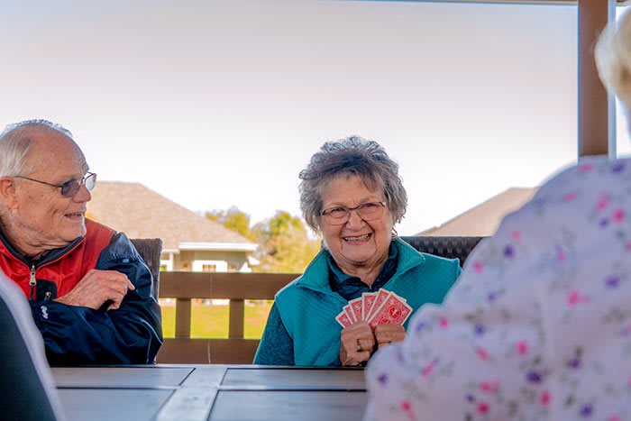 A group of elderly friends enjoying a card game outdoors on a sunny day.