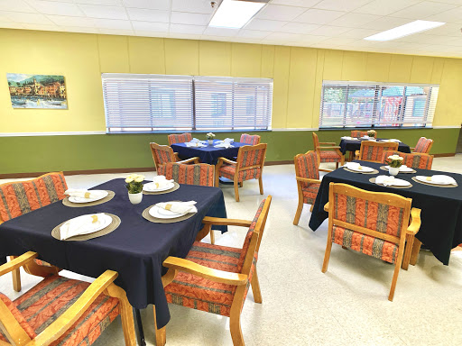 A neatly arranged dining room with tables set for a meal, featuring yellow walls and elegant decor.