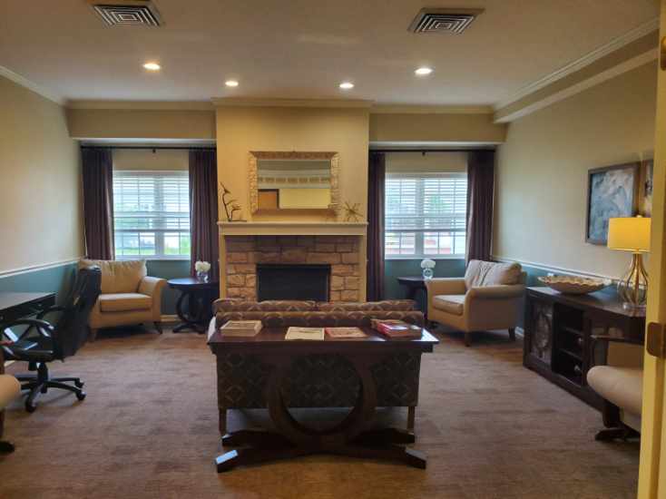 A cozy living room with a central fireplace, surrounded by sofas and chairs.