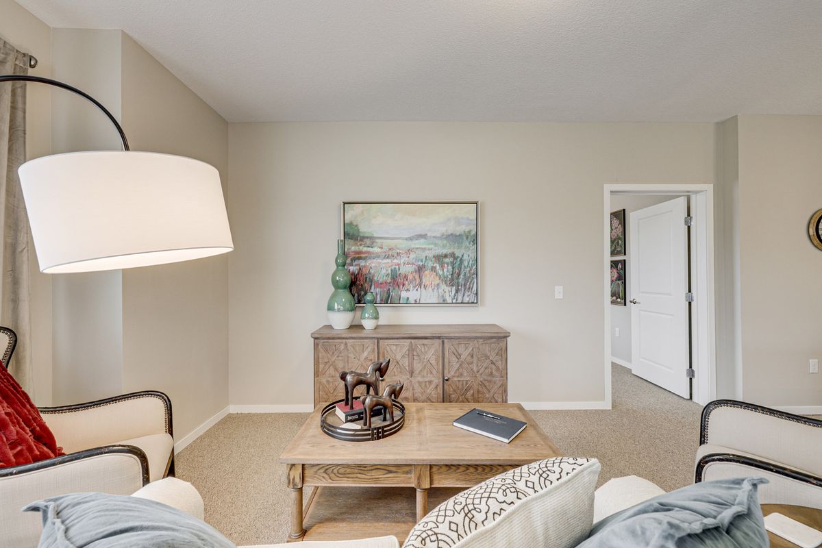 A cozy living room with neutral tones, featuring a large lamp, artwork on the wall, and a stylish coffee table.