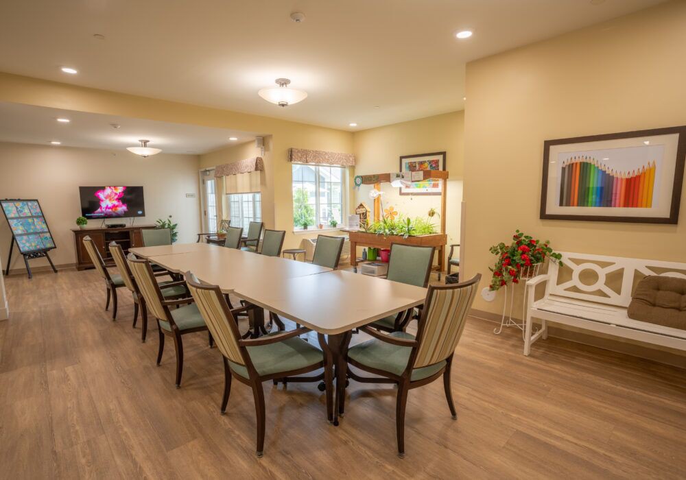 A spacious and well-lit dining area with a long table surrounded by chairs, featuring modern decor and artwork on the walls.