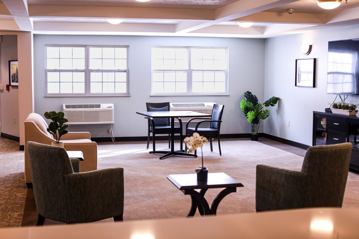 A modern lounge area with a table, chairs, and indoor plants.