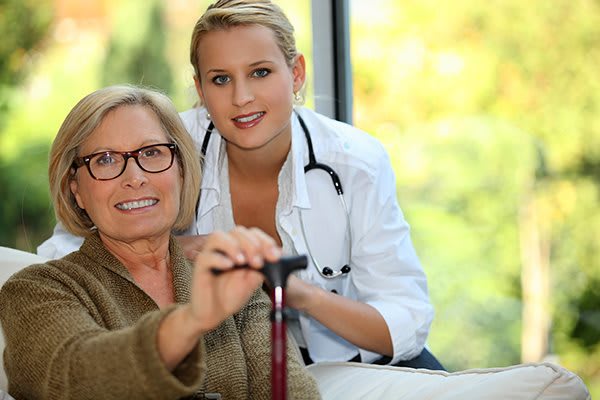 A medical professional assisting a senior woman at home.