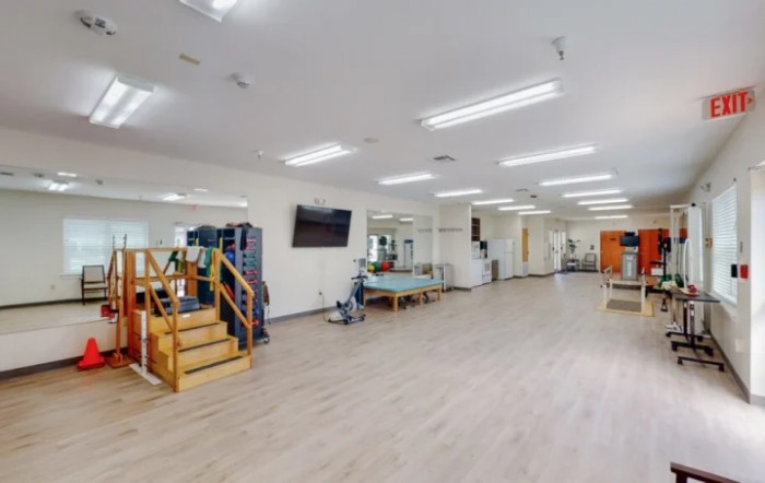 A spacious gym interior with exercise equipment and bright lighting.