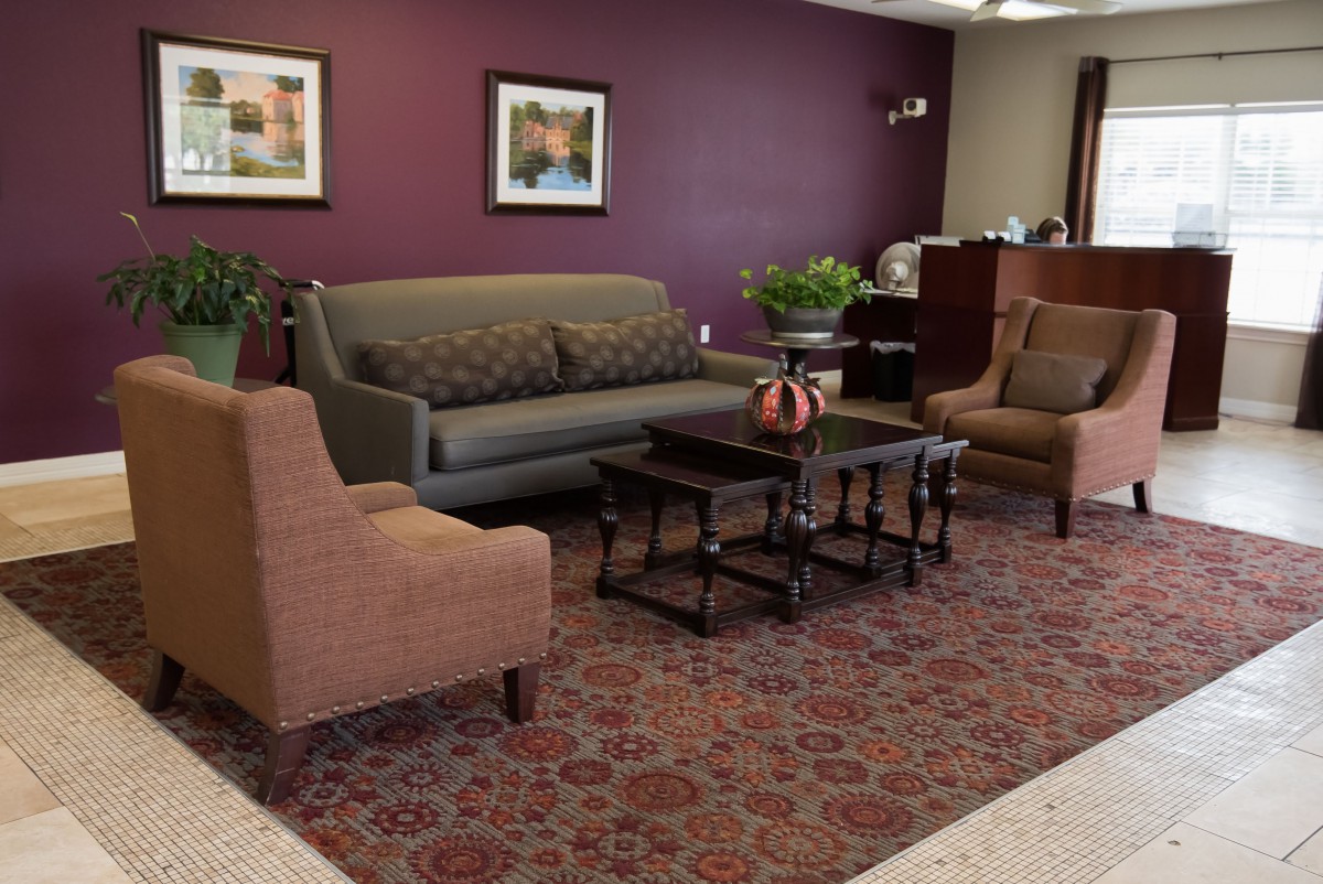 A cozy living room with a sofa, chairs, a coffee table, and decorative elements like framed art and indoor plants.