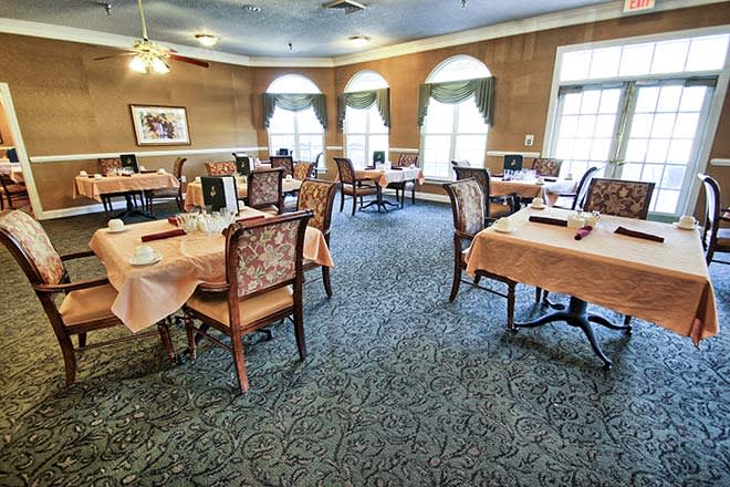 An elegant dining area with neatly arranged tables and chairs, featuring large windows and classic decor.