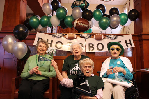 A joyful group of elderly women celebrating with Philadelphia Eagles themed decorations and props.