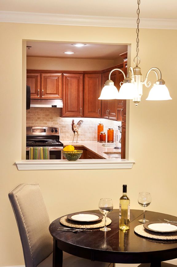 A cozy dining area with a view of the kitchen, featuring warm lighting and modern decor.