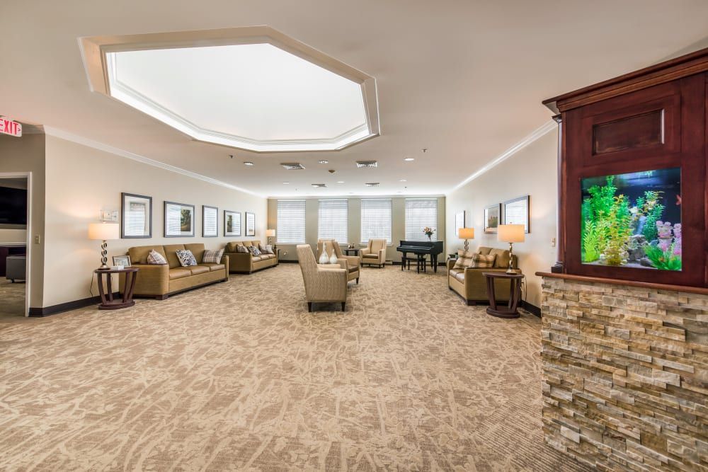 A spacious and elegantly decorated living room with multiple seating areas, featuring sofas, chairs, and a grand piano.