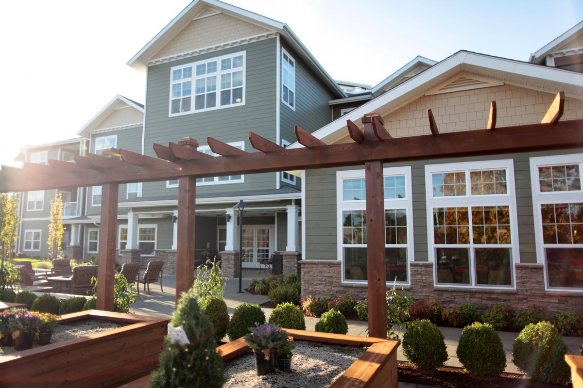 A modern residential building with a landscaped garden and wooden pergola.