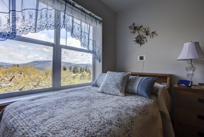 A cozy bedroom with a large window offering a scenic view.