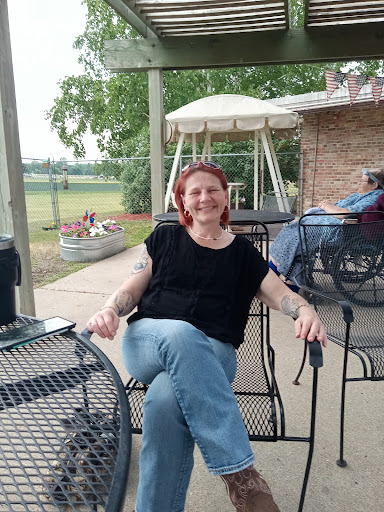 A woman enjoying a relaxing moment outdoors, seated comfortably on a chair with a pleasant background.
