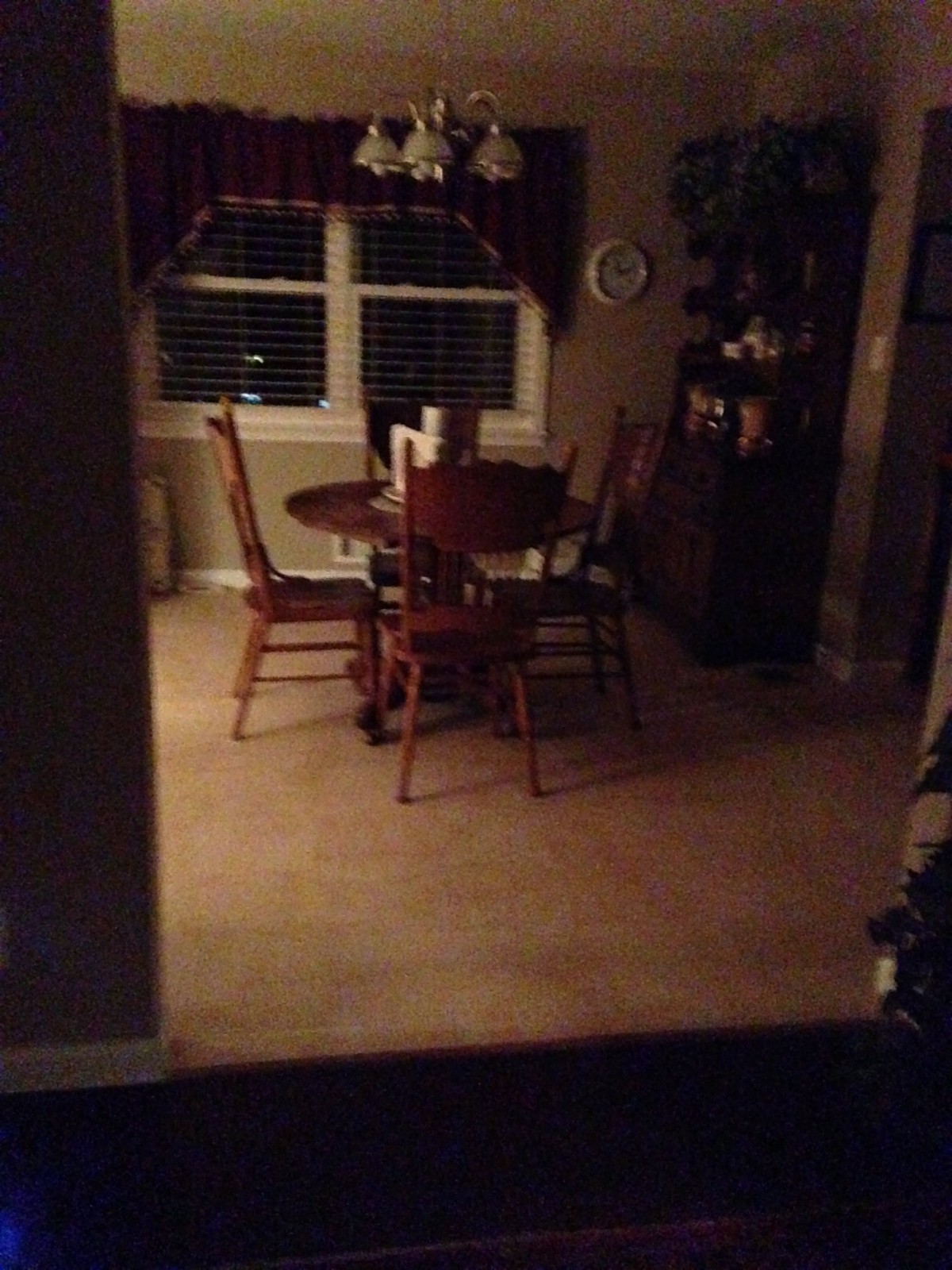A dimly lit dining room featuring a wooden table and chairs.