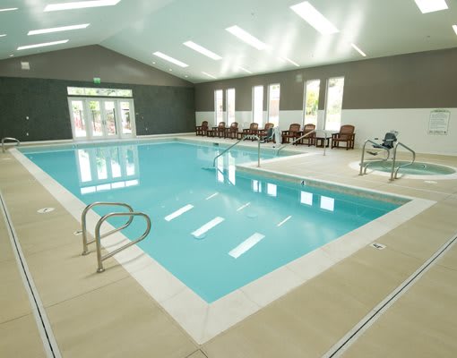 A serene indoor swimming pool with chairs along the side.
