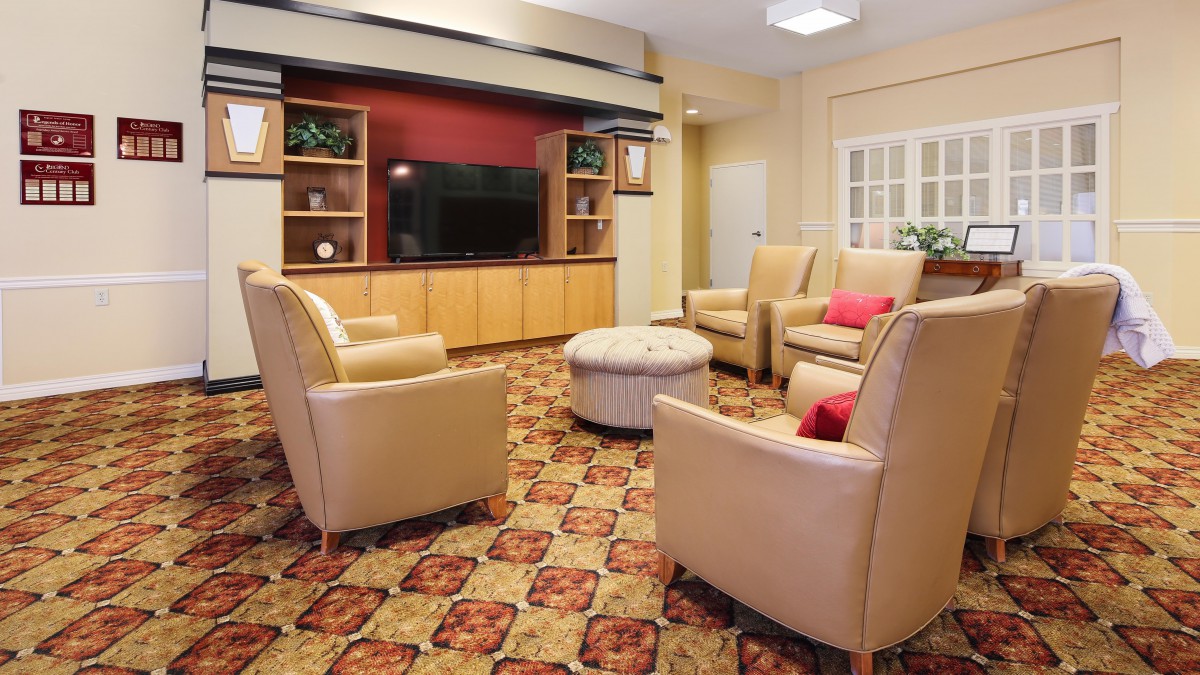 A cozy living room with comfortable armchairs, a television, and a patterned carpet.